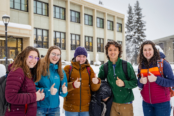 A group of students pose for a photo on a wintery ӰɴýF campus
